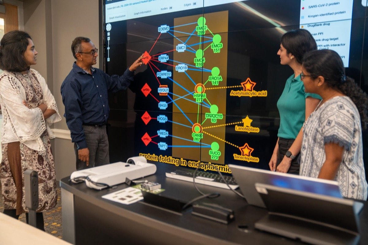 A research team discusses a complex protein-interaction visualization on a large display.
