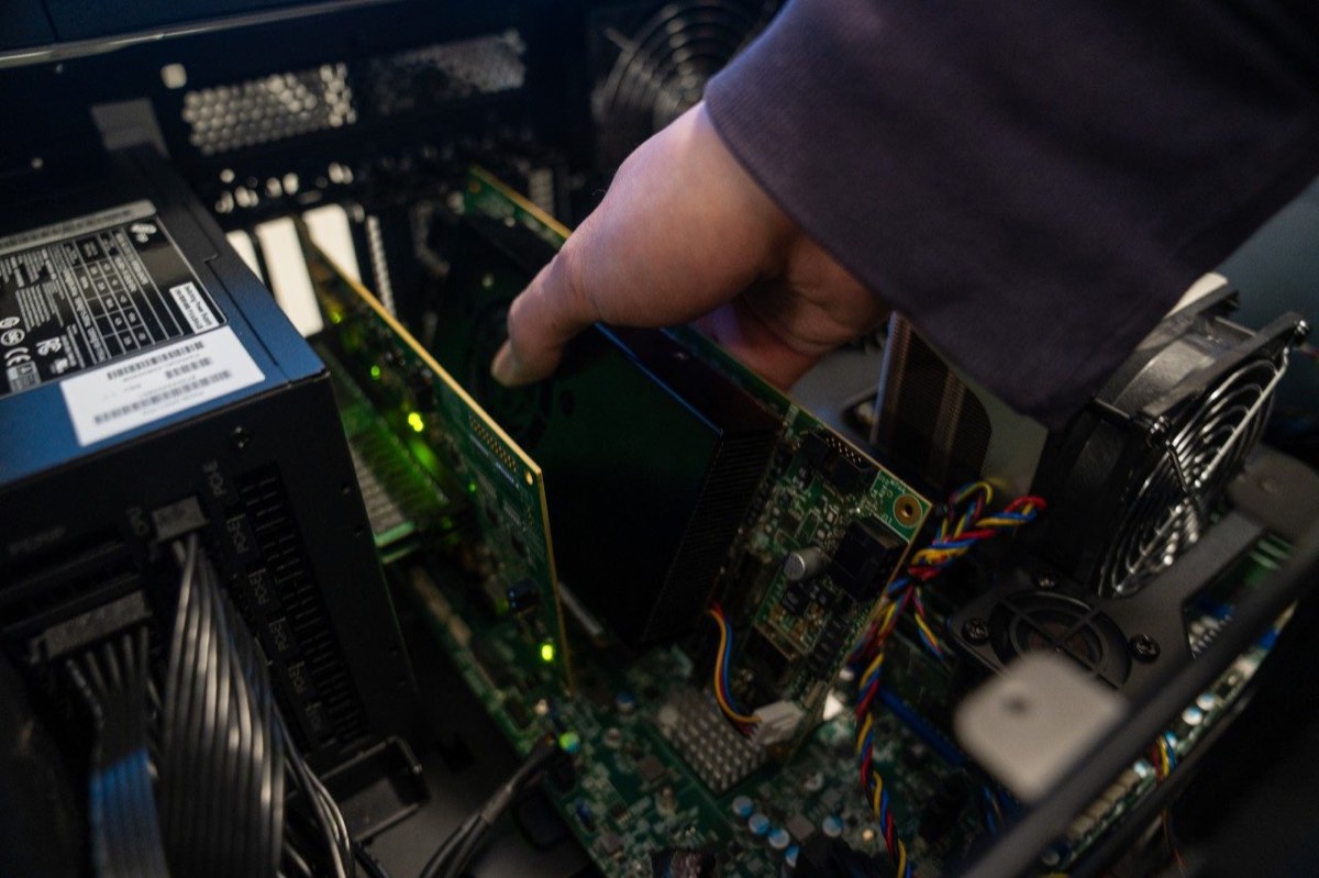A hand installs a component inside a computer server.
